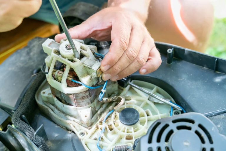 A man repairs a broken lawn mower on it's wirings.