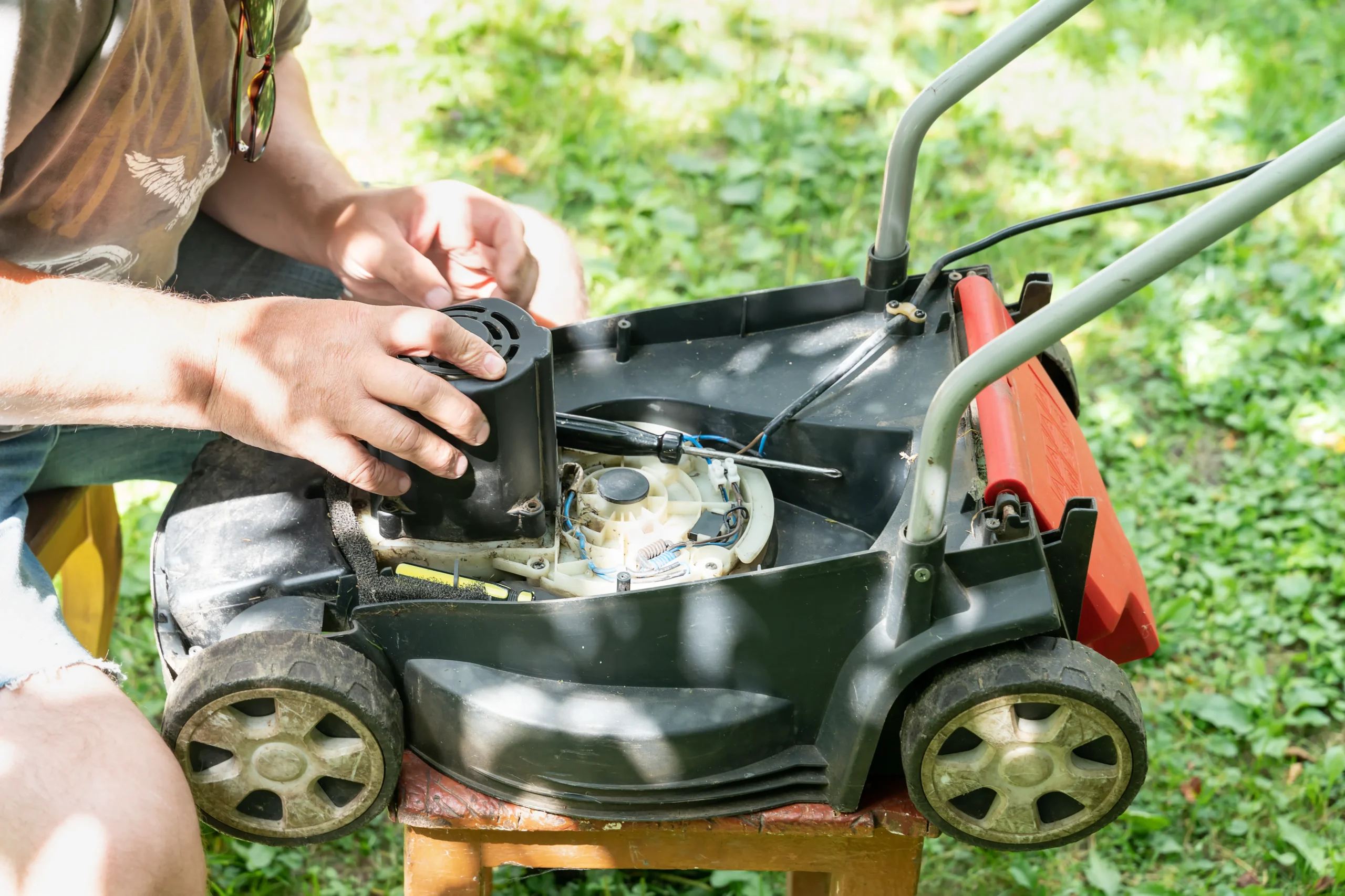 Repairman fixes the lawn mower engine with tools.