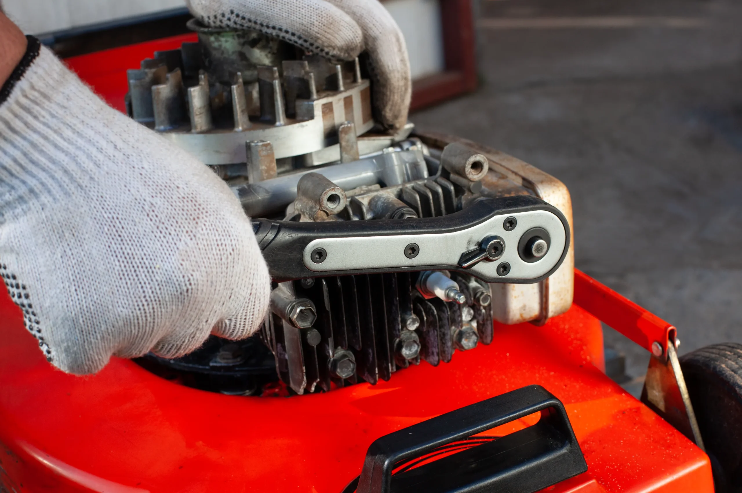 A lawn mower in the garage getting checked by the repairman.